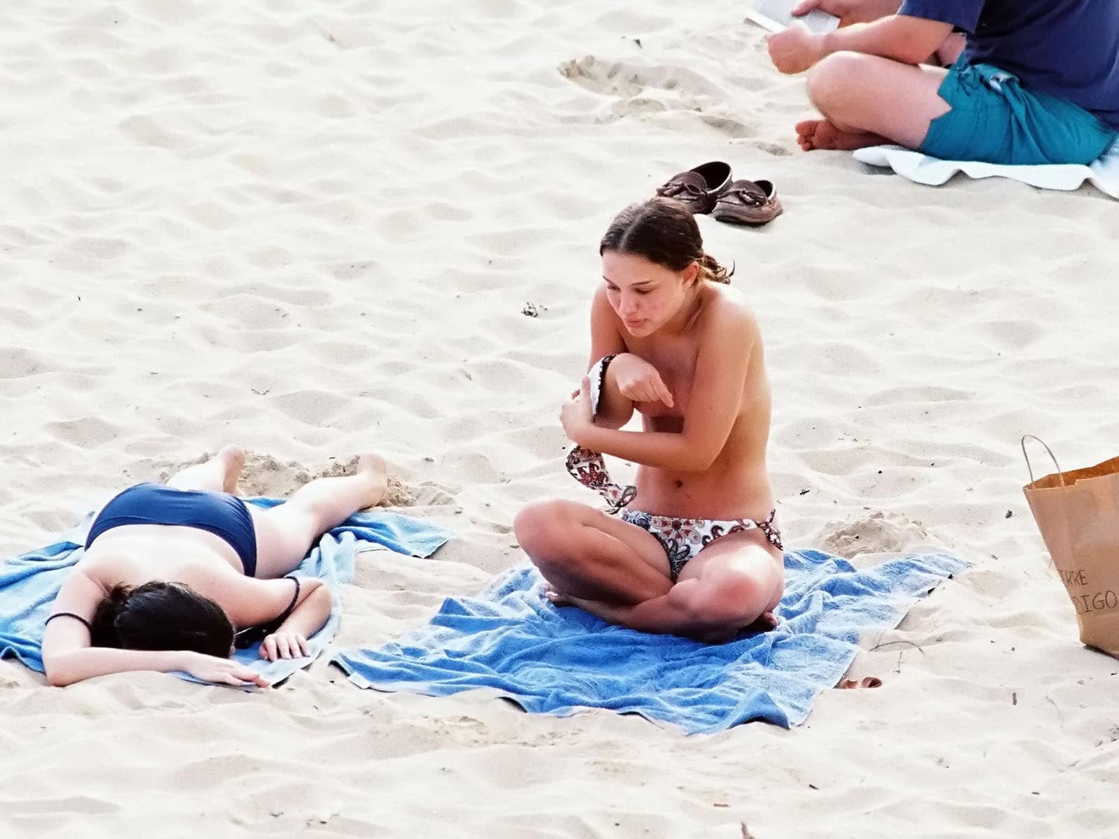 while laying on a beach towel natalie portman takes off her top